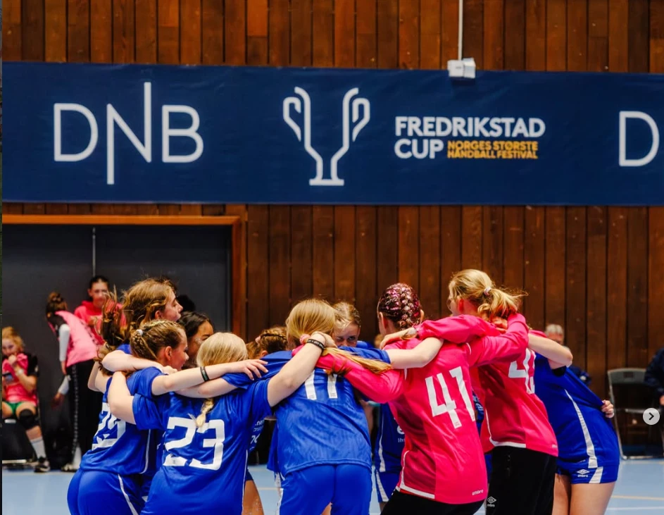 Håndballag foran banereklame for DNB og Fredrikstad Cup